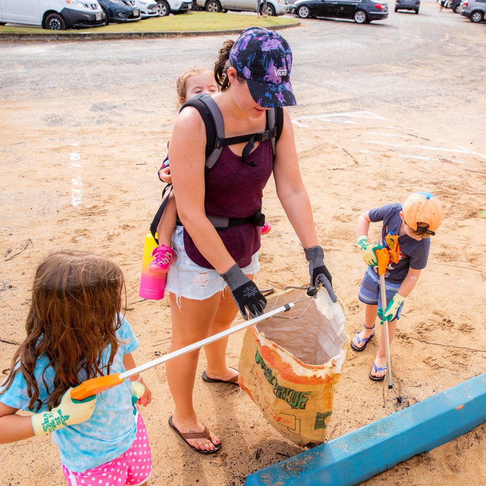 Photo of surfrider volunteers and children picking up trash at a beach cleanup  