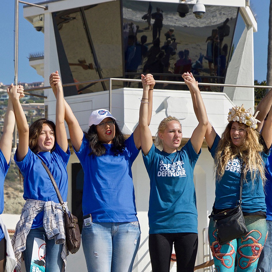 photo of surfrider volunteers holding hands at the beach 